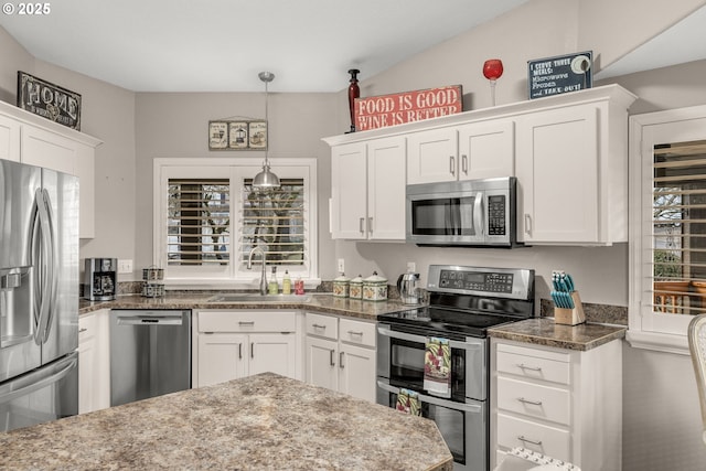 kitchen with pendant lighting, appliances with stainless steel finishes, dark stone countertops, and white cabinets