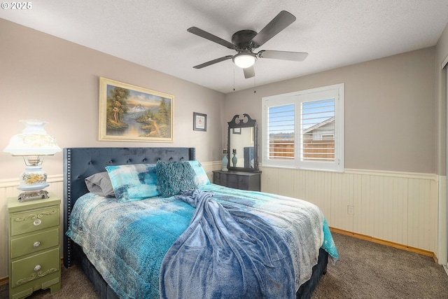 bedroom featuring ceiling fan, dark carpet, and a textured ceiling