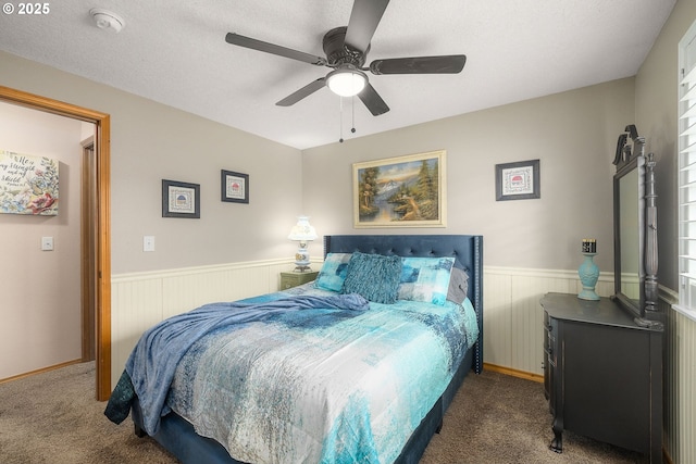 bedroom with dark colored carpet, ceiling fan, and a textured ceiling