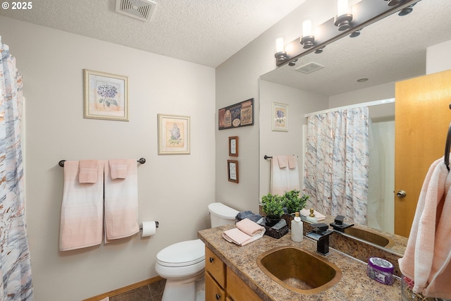 bathroom with vanity, toilet, tile patterned flooring, and a textured ceiling