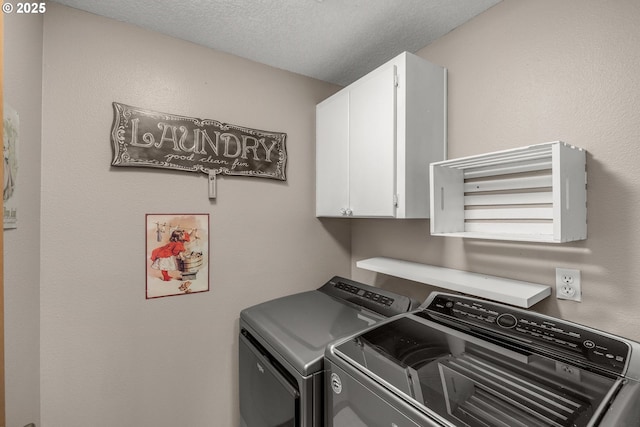 washroom with cabinets, washing machine and clothes dryer, and a textured ceiling