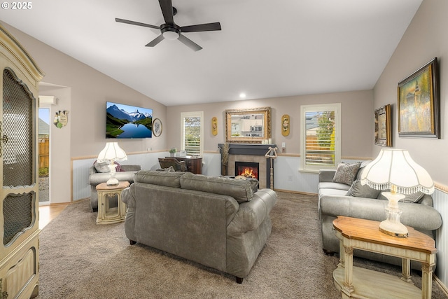 living room featuring a tiled fireplace, lofted ceiling, light colored carpet, and ceiling fan