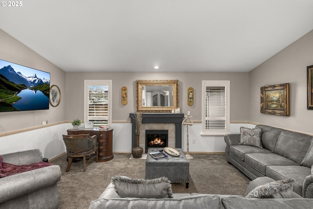 living room featuring a tiled fireplace, lofted ceiling, and carpet