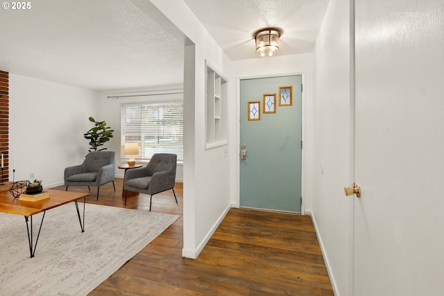 foyer entrance with a textured ceiling, dark wood-type flooring, and baseboards