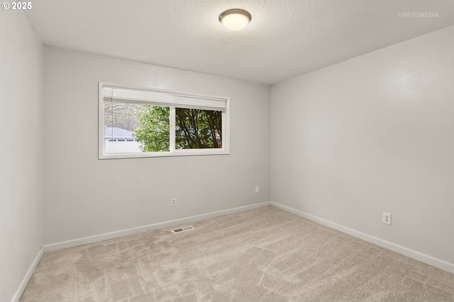 carpeted spare room with baseboards, visible vents, and a textured ceiling