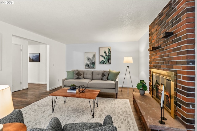 living area with a fireplace, a textured ceiling, baseboards, and wood finished floors