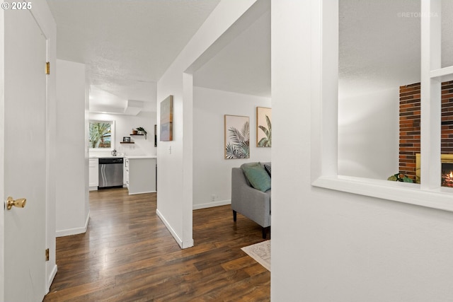 hall with a textured ceiling, baseboards, and dark wood-style flooring