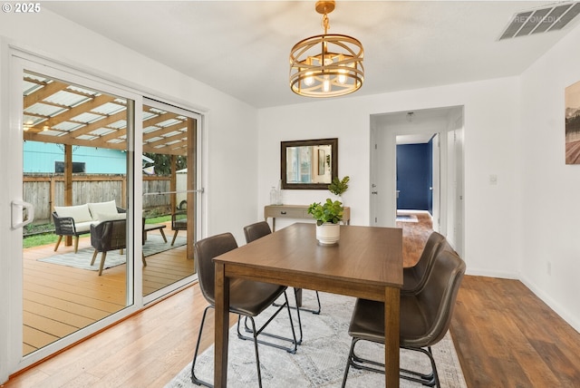 dining area with baseboards, light wood-style flooring, visible vents, and a notable chandelier