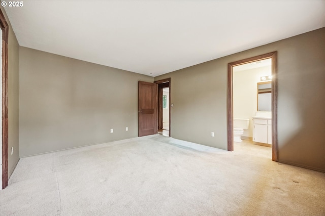 unfurnished bedroom featuring ensuite bath and light colored carpet