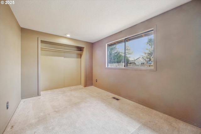 unfurnished bedroom with visible vents, a closet, and carpet flooring