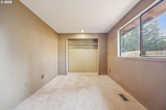 unfurnished bedroom with baseboards, visible vents, elevator, a closet, and carpet flooring