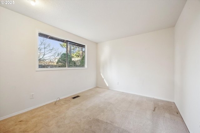 carpeted spare room featuring visible vents and baseboards