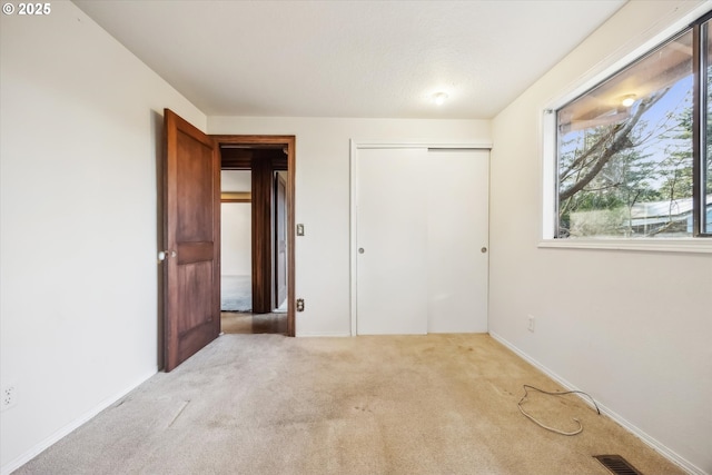 unfurnished bedroom with a closet, visible vents, and carpet flooring