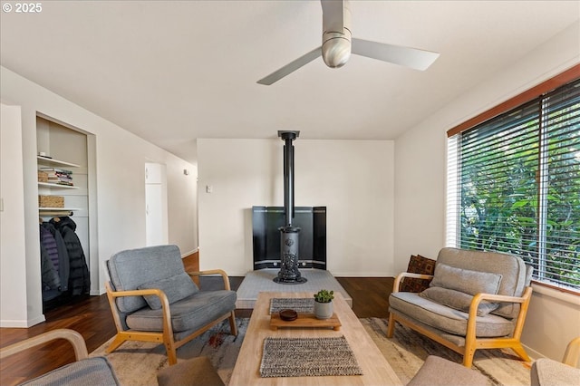 living room with ceiling fan, plenty of natural light, built in features, and a wood stove