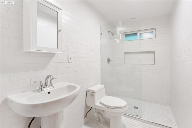 bathroom featuring sink, tile walls, tile patterned flooring, tiled shower, and toilet