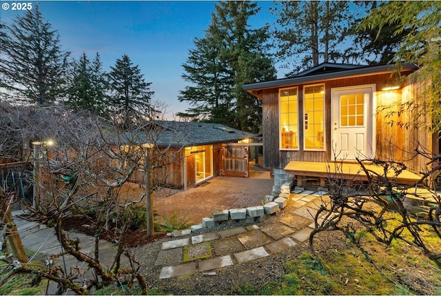 back house at dusk with a deck and a patio