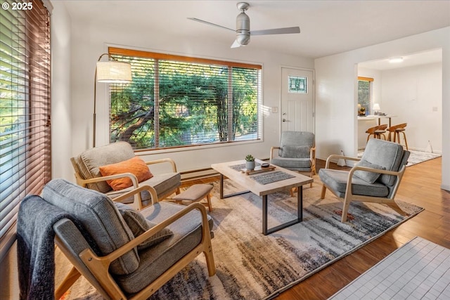 living area featuring ceiling fan, a baseboard heating unit, and light wood-type flooring