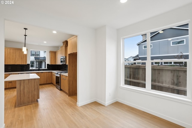 kitchen with a kitchen island, stainless steel appliances, light countertops, pendant lighting, and backsplash