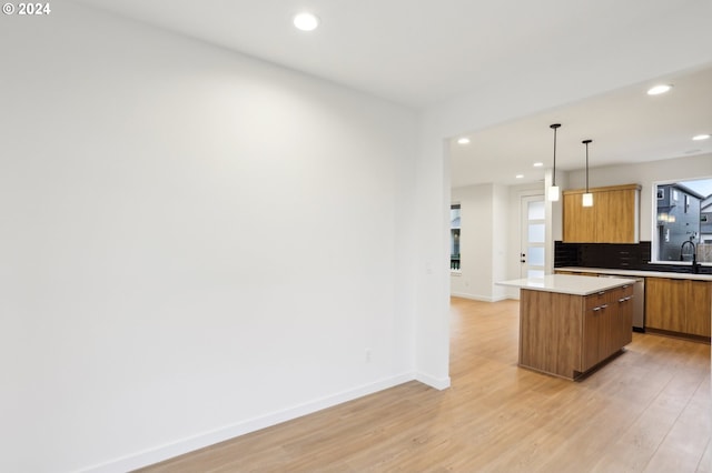 kitchen with a kitchen island, light countertops, light wood-type flooring, brown cabinets, and pendant lighting