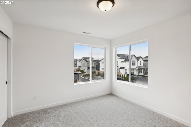 unfurnished room with visible vents, carpet floors, a residential view, and baseboards