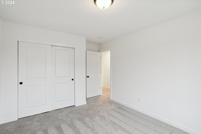 unfurnished bedroom with light carpet, baseboards, and a closet