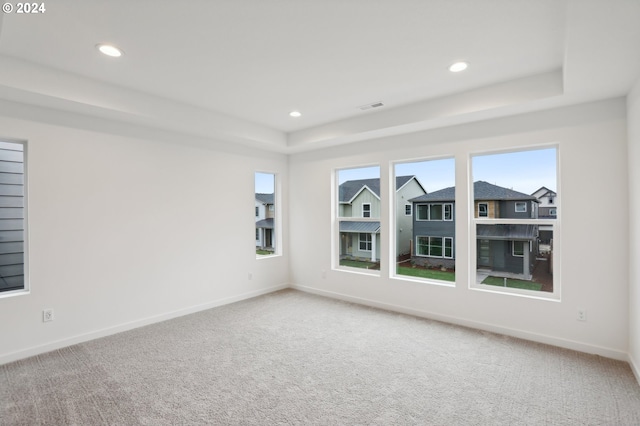 carpeted spare room with recessed lighting, a raised ceiling, visible vents, and baseboards