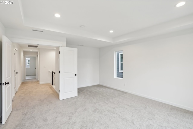 spare room with recessed lighting, light colored carpet, visible vents, baseboards, and a tray ceiling