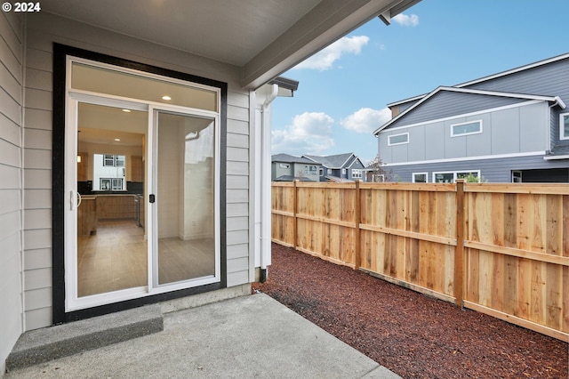 doorway to property with a residential view, fence, and a patio