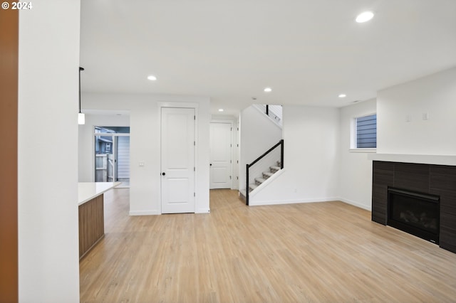 unfurnished living room with light wood-style flooring, recessed lighting, a fireplace, baseboards, and stairs