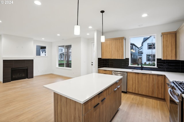 kitchen with a center island, stainless steel appliances, light countertops, pendant lighting, and a sink