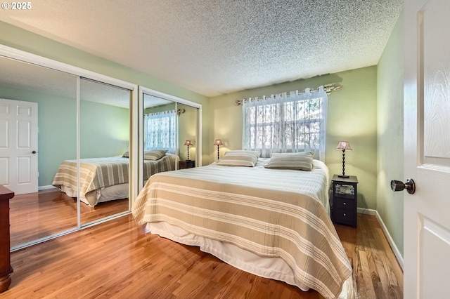 2433 NE Saratoga St, Portland, OR 97211 - bedroom featuring multiple closets, baseboards, a textured ceiling, and wood finished floors