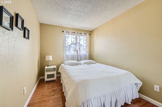 2433 NE Saratoga St, Portland, OR 97211 - bedroom featuring baseboards, a textured ceiling, a textured wall, and wood finished floors