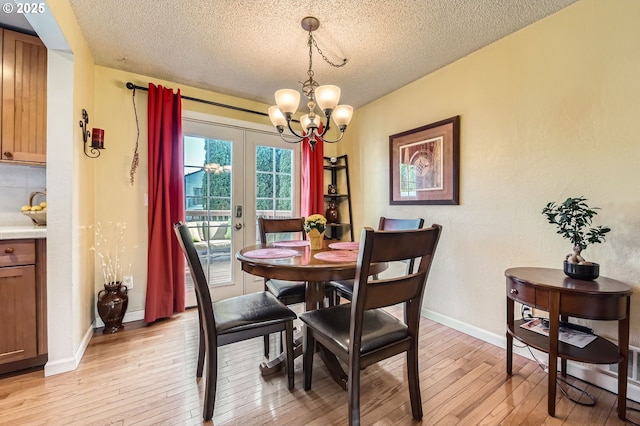 2433 NE Saratoga St, Portland, OR 97211 - dining area with an inviting chandelier, a textured ceiling, baseboards, and light wood-style flooring