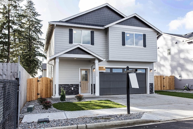 craftsman house featuring concrete driveway, a gate, fence, and stone siding