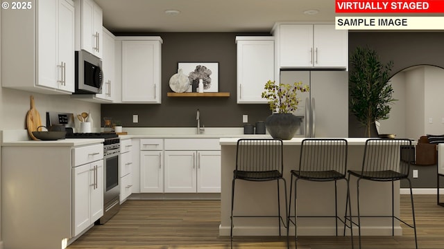 856 Eaden St, Woodburn, OR 97071 - kitchen with stainless steel appliances, a kitchen breakfast bar, white cabinets, light wood-style flooring, and a kitchen island