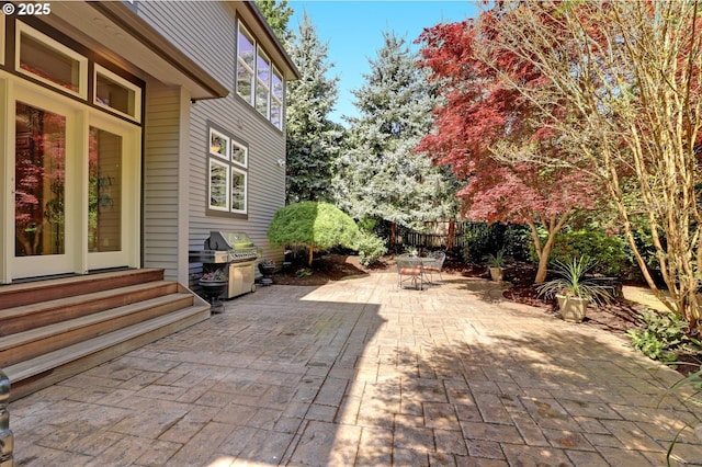 view of patio with area for grilling, fence, outdoor dining area, and entry steps