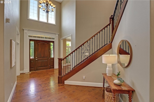 entrance foyer featuring stairs, a chandelier, a wealth of natural light, and hardwood / wood-style flooring