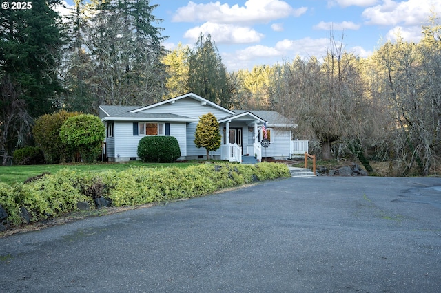 ranch-style home featuring covered porch and a front lawn