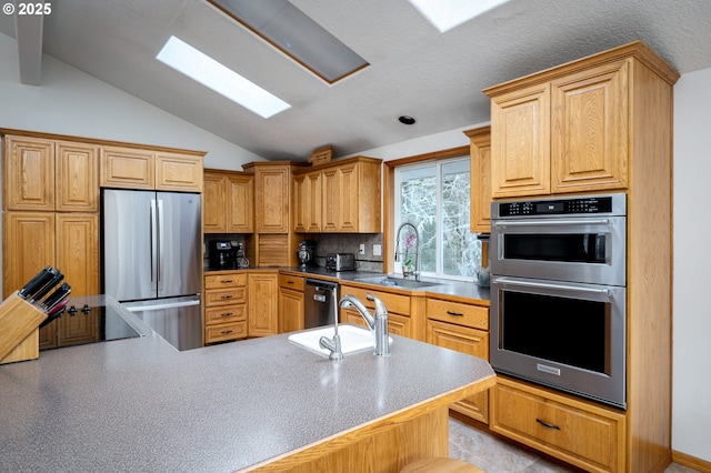 kitchen featuring backsplash, sink, stainless steel appliances, and vaulted ceiling