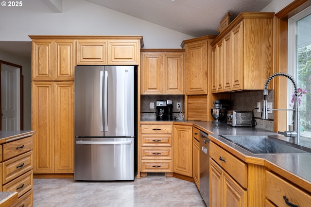 kitchen featuring decorative backsplash, sink, lofted ceiling, and appliances with stainless steel finishes