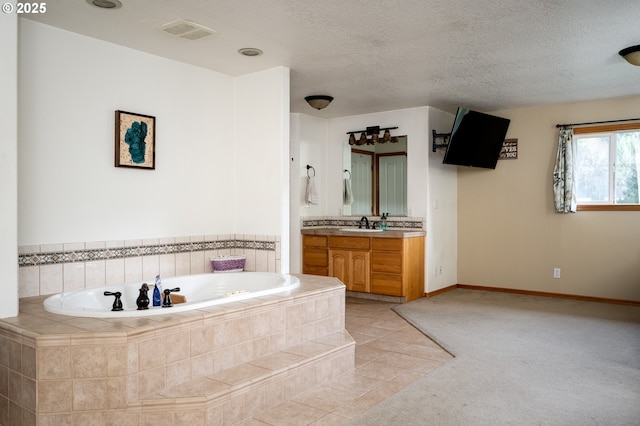 bathroom with tile patterned floors, vanity, a textured ceiling, and tiled bath