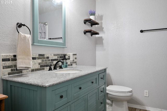 bathroom featuring vanity, wood-type flooring, backsplash, and toilet