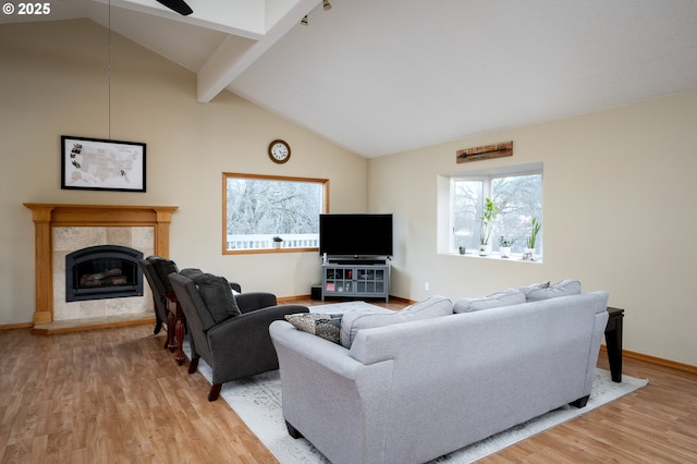 living room featuring wood-type flooring, lofted ceiling with beams, and a tiled fireplace