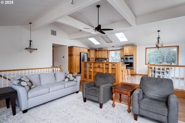 living room featuring light hardwood / wood-style flooring, ceiling fan, lofted ceiling with skylight, and sink