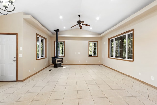 unfurnished living room featuring ceiling fan, vaulted ceiling, light tile patterned flooring, and a wood stove