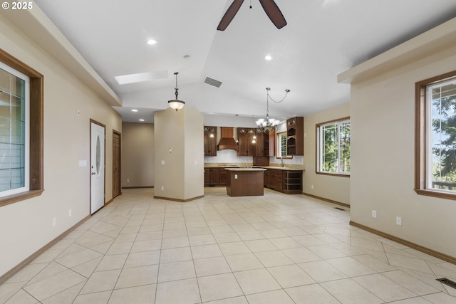 kitchen with pendant lighting, a center island, vaulted ceiling with skylight, custom range hood, and ceiling fan with notable chandelier