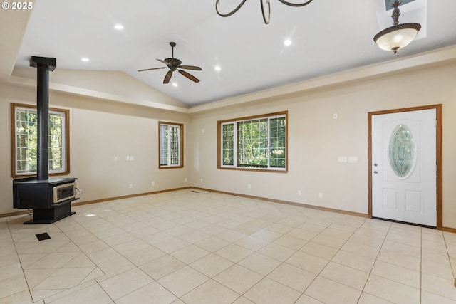 unfurnished living room featuring ceiling fan, vaulted ceiling, a wood stove, and light tile patterned floors