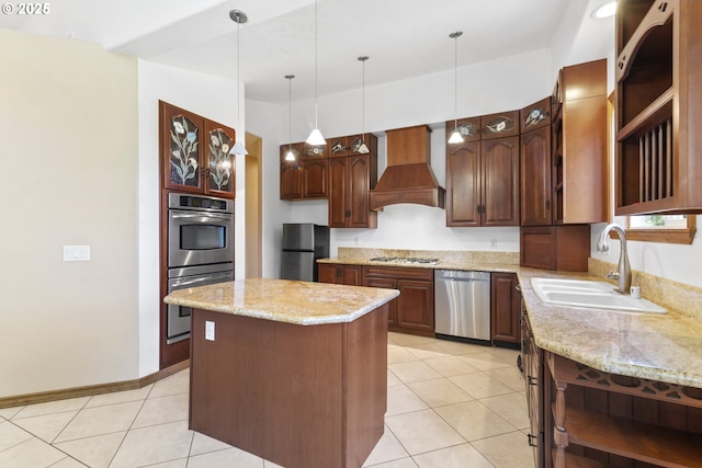 kitchen with decorative light fixtures, wall chimney range hood, a kitchen island, appliances with stainless steel finishes, and sink