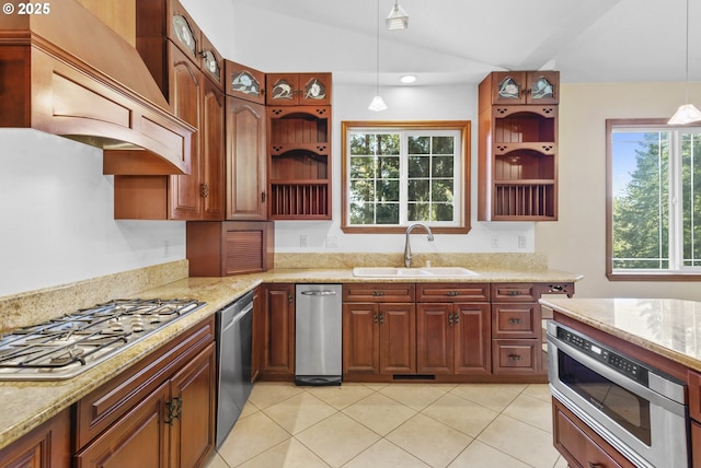 kitchen featuring light stone counters, hanging light fixtures, custom range hood, appliances with stainless steel finishes, and sink