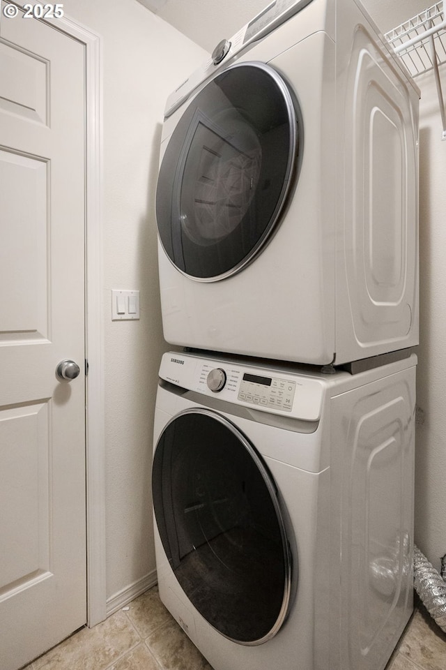 clothes washing area with light tile patterned floors, stacked washer / drying machine, and laundry area